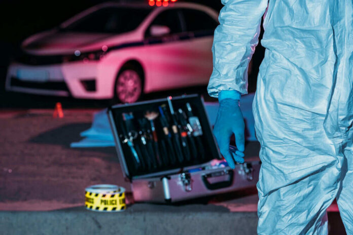 213023162-1 Forensic investigator at crime scene with police car.