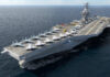 Aircraft carrier sailing at sea with jets lined up on the flight deck