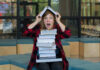 Person balancing books on head, looking surprised.