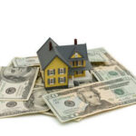 Model house on scattered US dollar bills