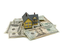 Model house on scattered US dollar bills