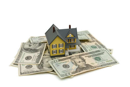 Model house on scattered US dollar bills