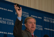 Aortic Shock Rocks Capitol Man holding phone at National Press Club event
