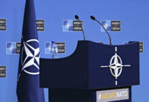 Trump Ultimatum Jolts NATO NATO podium with flags and microphones.