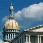 Capitol-style dome and neoclassical building facade under blue sky