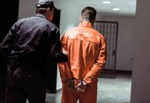 Police officer escorting handcuffed inmate in orange jumpsuit