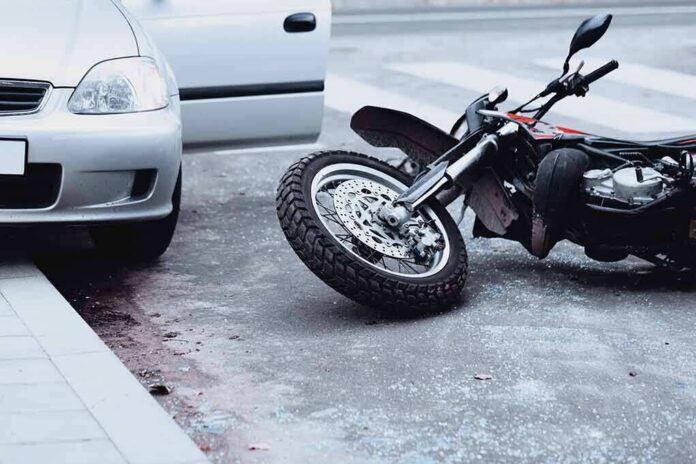 Motorcycle lying on the street beside a car with an open door