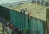 Ceuta Chaos Ignites Europe-Wide Fight People climbing a tall beachside border fence