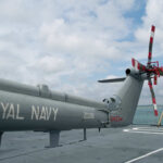 Military helicopter on a naval deck with a cloudy sky