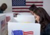Voters at polling booths with American flag in background