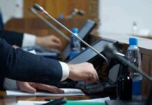 Army Axes Free Disability Lawyers Person pressing a button on a conference microphone panel
