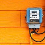 ROE Games: Households Get Squeezed Electric meter on bright orange wooden wall