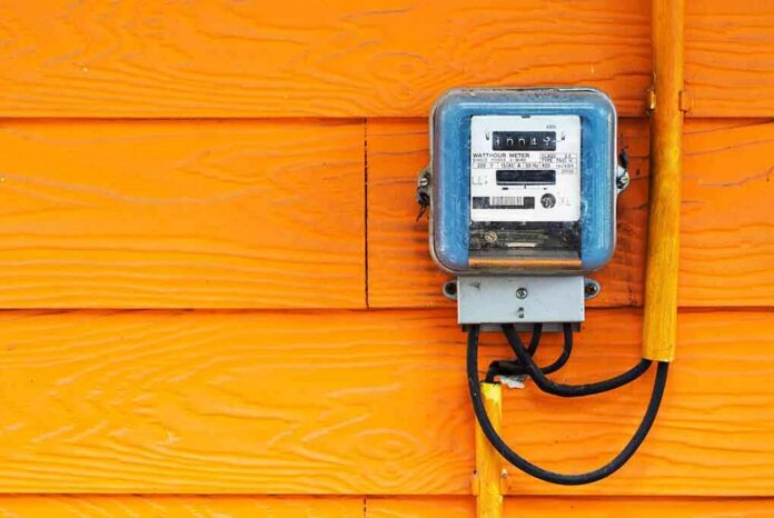 Electric meter on bright orange wooden wall