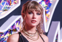 Woman with bangs wearing layered necklaces, colorful background.