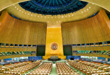 United Nations General Assembly hall with empty seats and golden backdrop