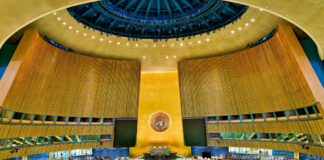 United Nations General Assembly hall with empty seats and golden backdrop