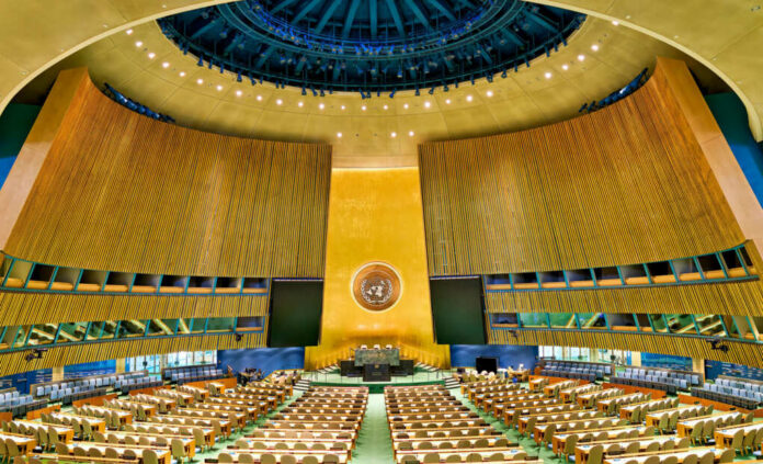 United Nations General Assembly hall with empty seats and golden backdrop