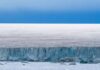 Ice cliff along a polar glacier under a blue sky