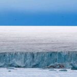 Ice cliff along a polar glacier under a blue sky