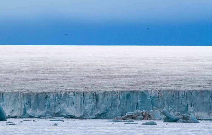 Ice cliff along a polar glacier under a blue sky