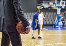 Basketball coach in suit holding ball courtside