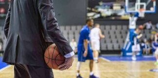 Basketball coach in suit holding ball courtside
