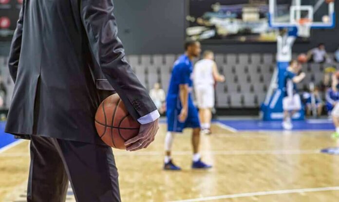 Basketball coach in suit holding ball courtside