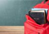 Red backpack with books on a classroom desk