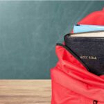 Bible Fight Erupts Over Health Care Red backpack with books on a classroom desk