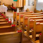 Empty wooden church pews with red hymnals