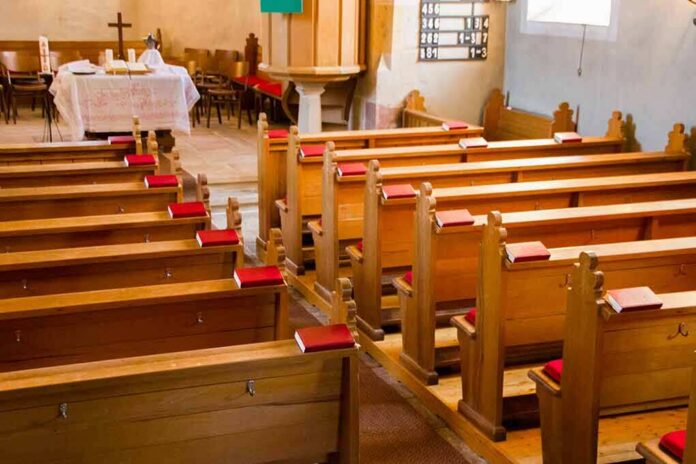 Empty wooden church pews with red hymnals