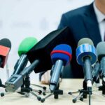 microphones clustered on a table at a press conference