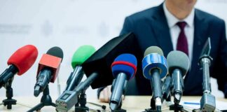 microphones clustered on a table at a press conference