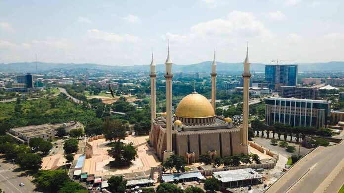 shutterstock_1439453054-1 Golden-domed mosque with four minarets in a modern cityscape