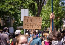 Abolish Prisons? No Plan for Rapists Protesters holding signs and wearing masks at an outdoor rally