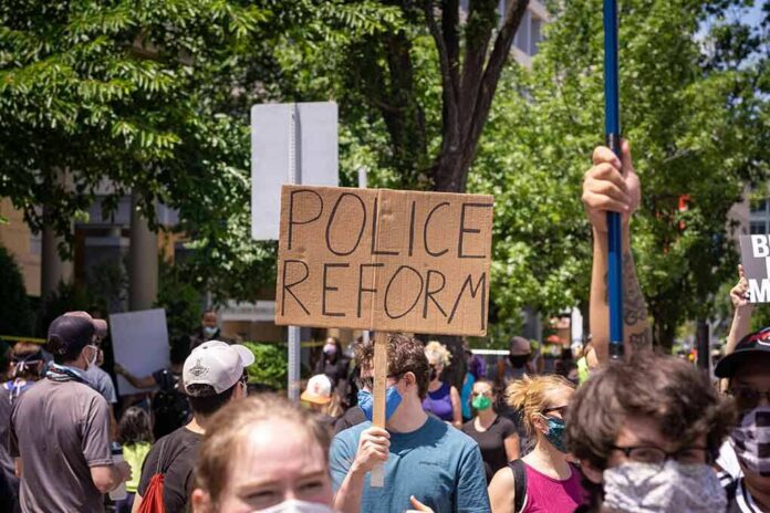 shutterstock_1752907970-1 Protesters holding signs and wearing masks at an outdoor rally