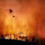 Helicopter fights massive wildfire over burning forest