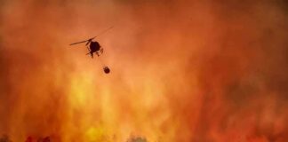 Helicopter fights massive wildfire over burning forest