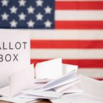 Ballot box with papers in front of an American flag