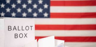 Ballot box with papers in front of an American flag