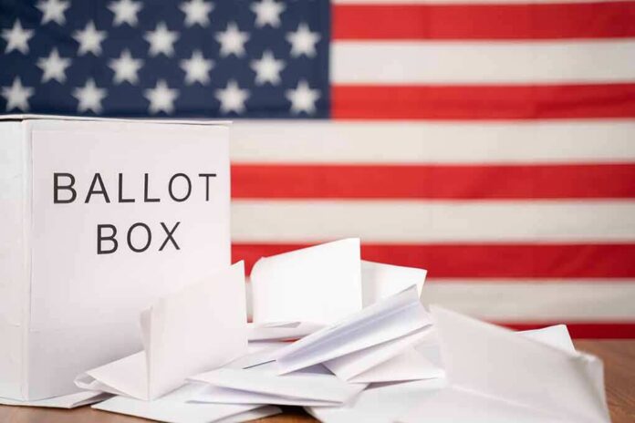shutterstock_1818888026-1 Ballot box with papers in front of an American flag