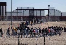 Abbey Gate Accounts Clash Over Preventable Tragedy Crowd of people lining up near a border fence with barbed wire