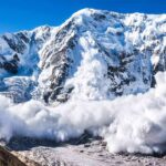 Snow avalanche sweeping down a rugged mountain