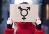 Person holding cardboard sign with gender symbol