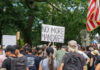 Crowd holds No More Mandates sign at protest.