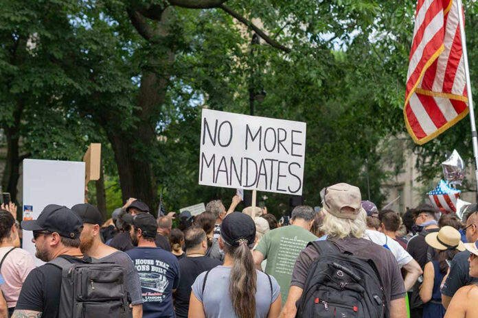 Crowd holds No More Mandates sign at protest.