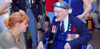Elderly veteran in wheelchair greeted by woman