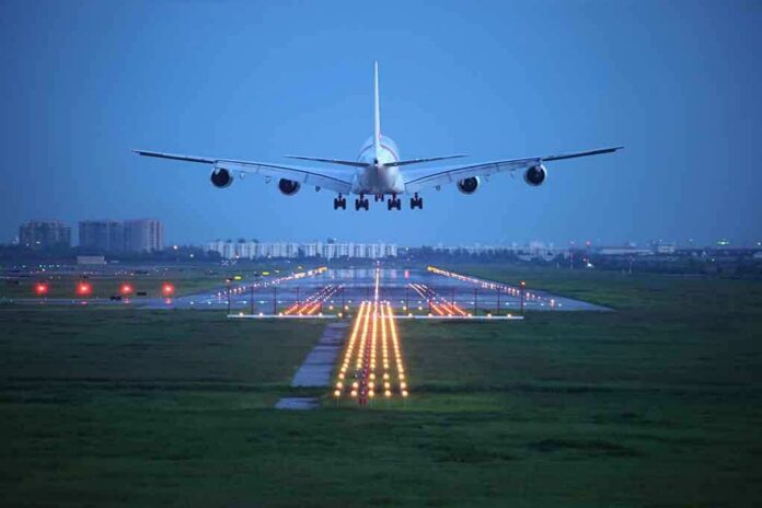 An airplane approaching the runway at night with landing lights illuminated