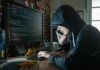 Bitcoin Heist Twist: Thief Gives It Back Person in hoodie using computer and phone at desk