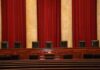 Congress Takes Aim at War Powers Empty courtroom bench with red curtains and leather chairs
